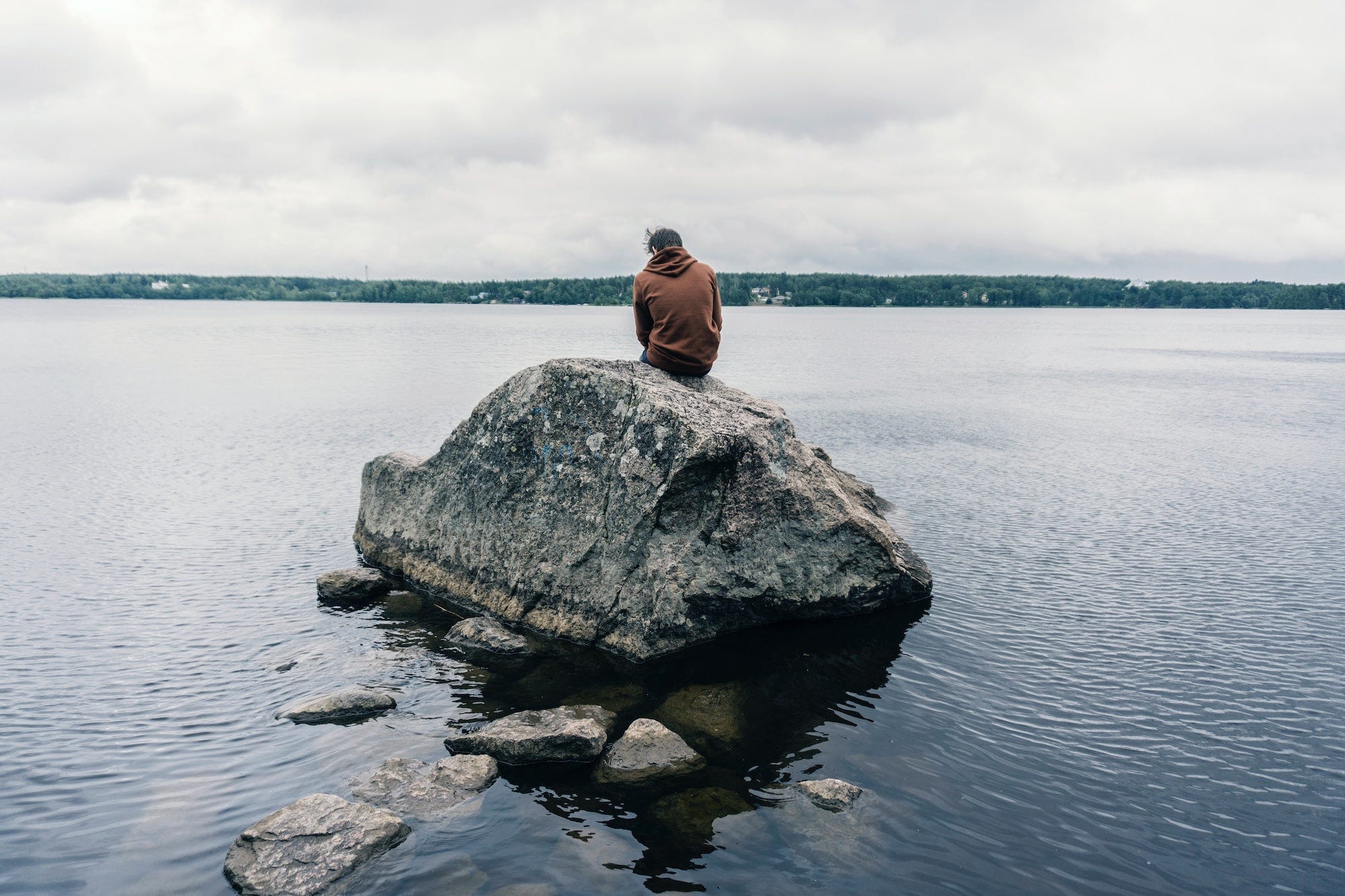 A photo of a man sitting on a rock on the coast of Baltic sea in Baltic gulf.