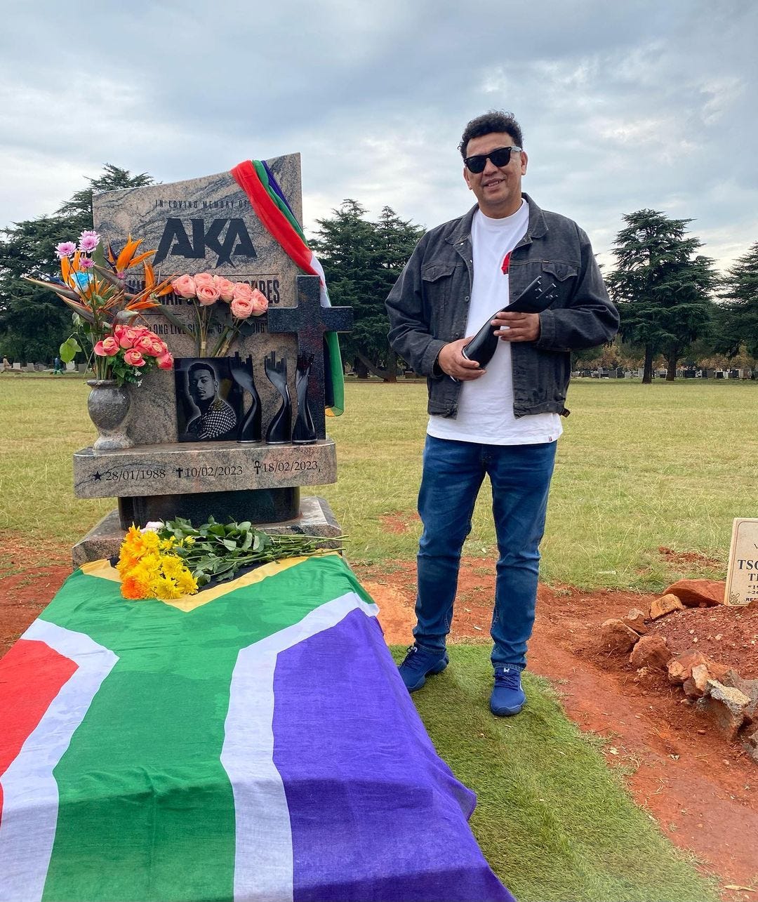 AKA's dad standing by his late son's grave with an award