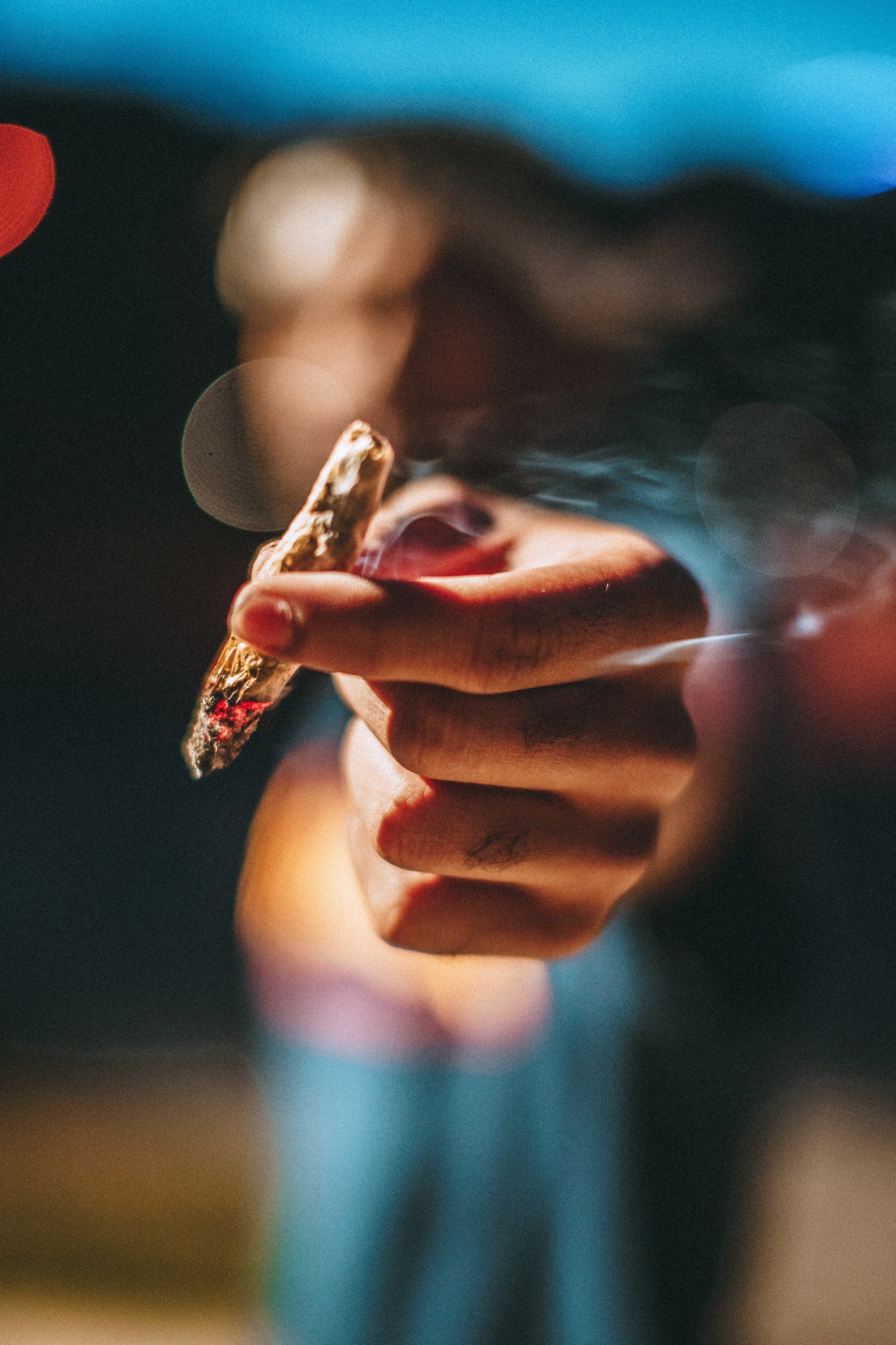 An image of a blurred out man handing someone else a cannabis cigarette