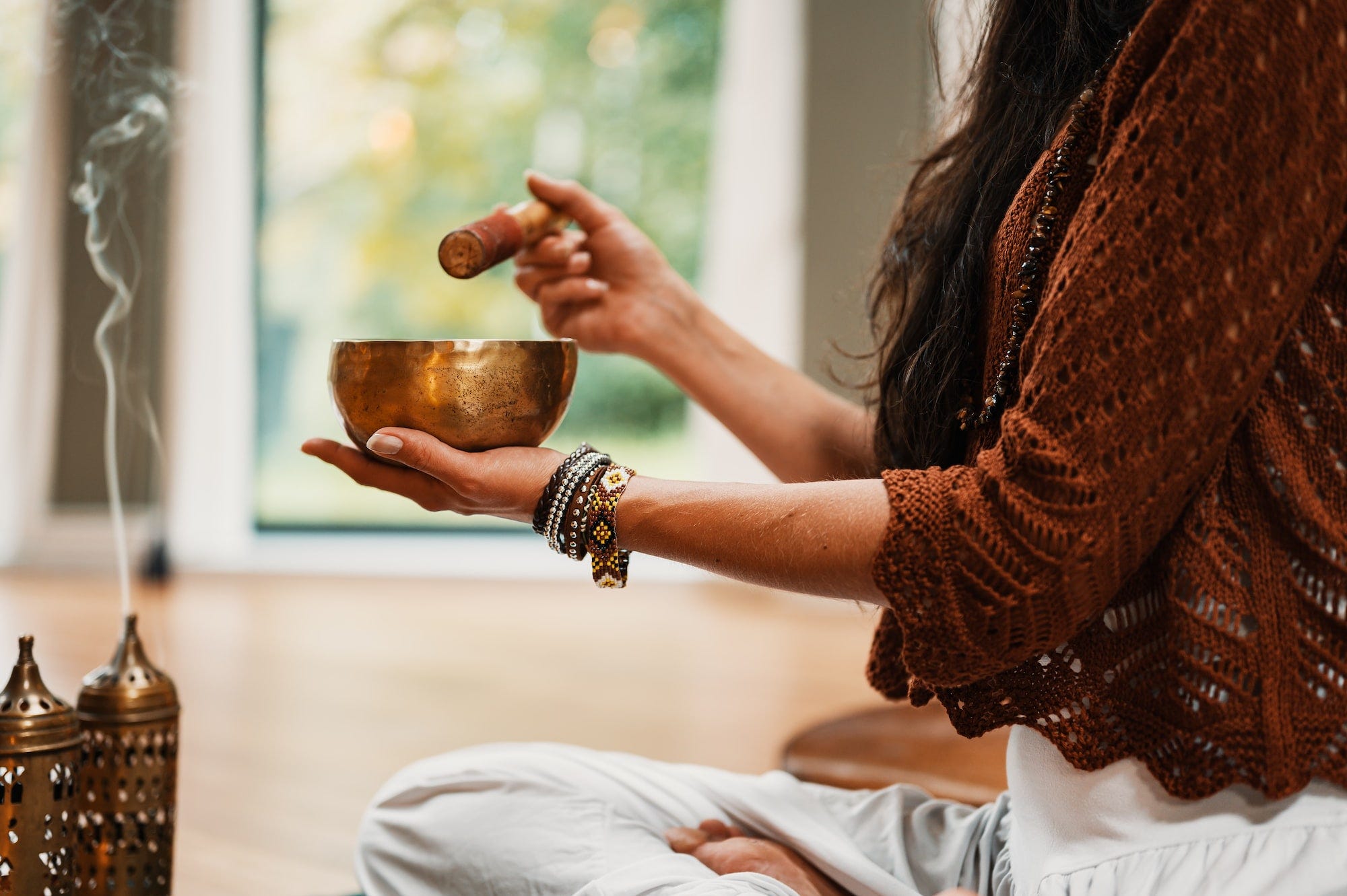 A woman meditating using a singing bowl