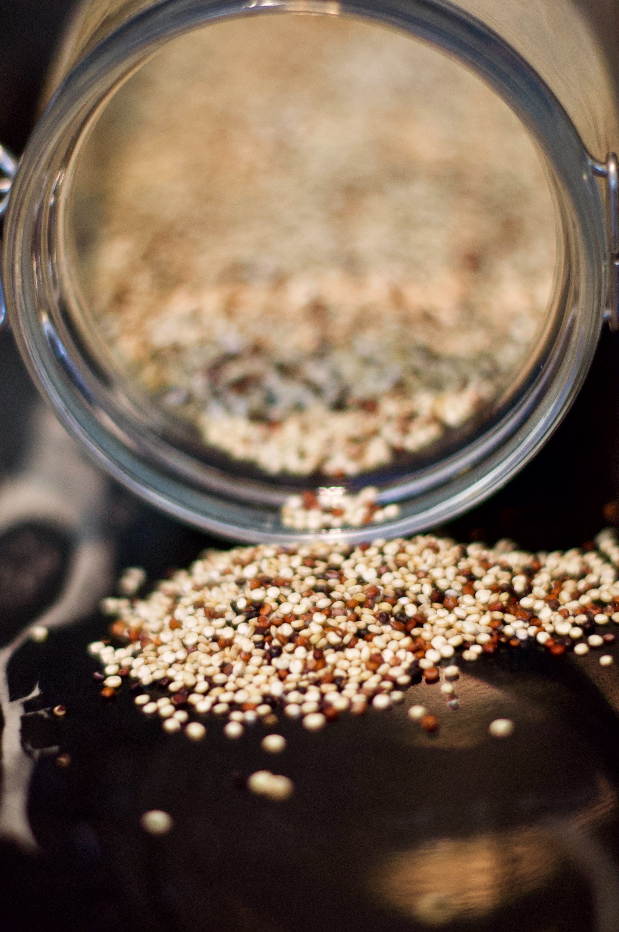 A jar of Quinoa seeds pouring the seeds onto a table