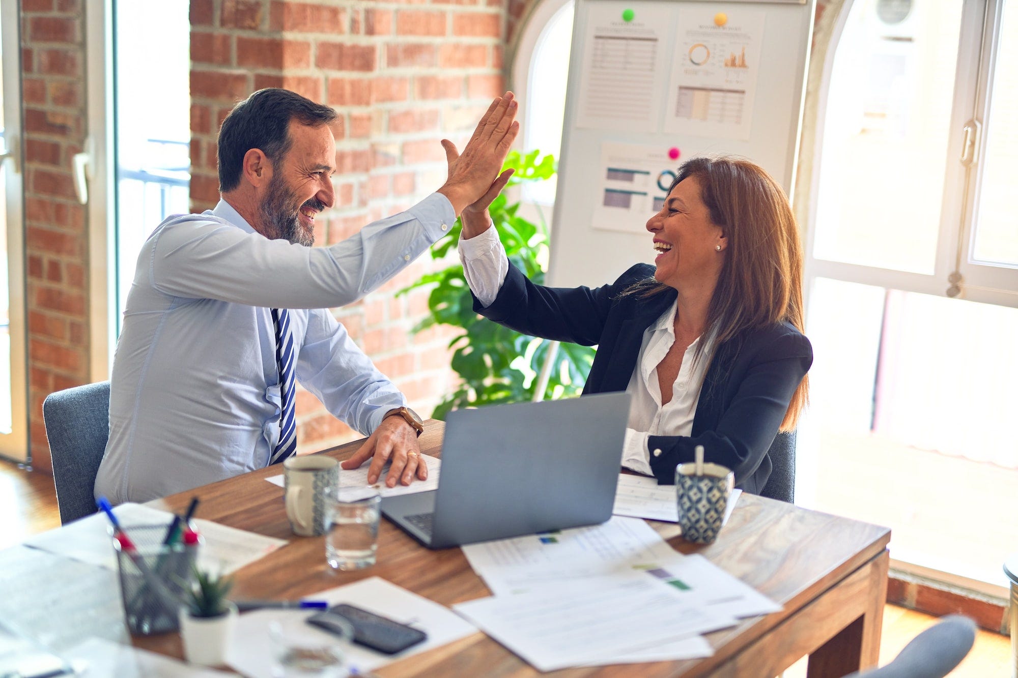 A man and woman working together and gleefuly high five each other