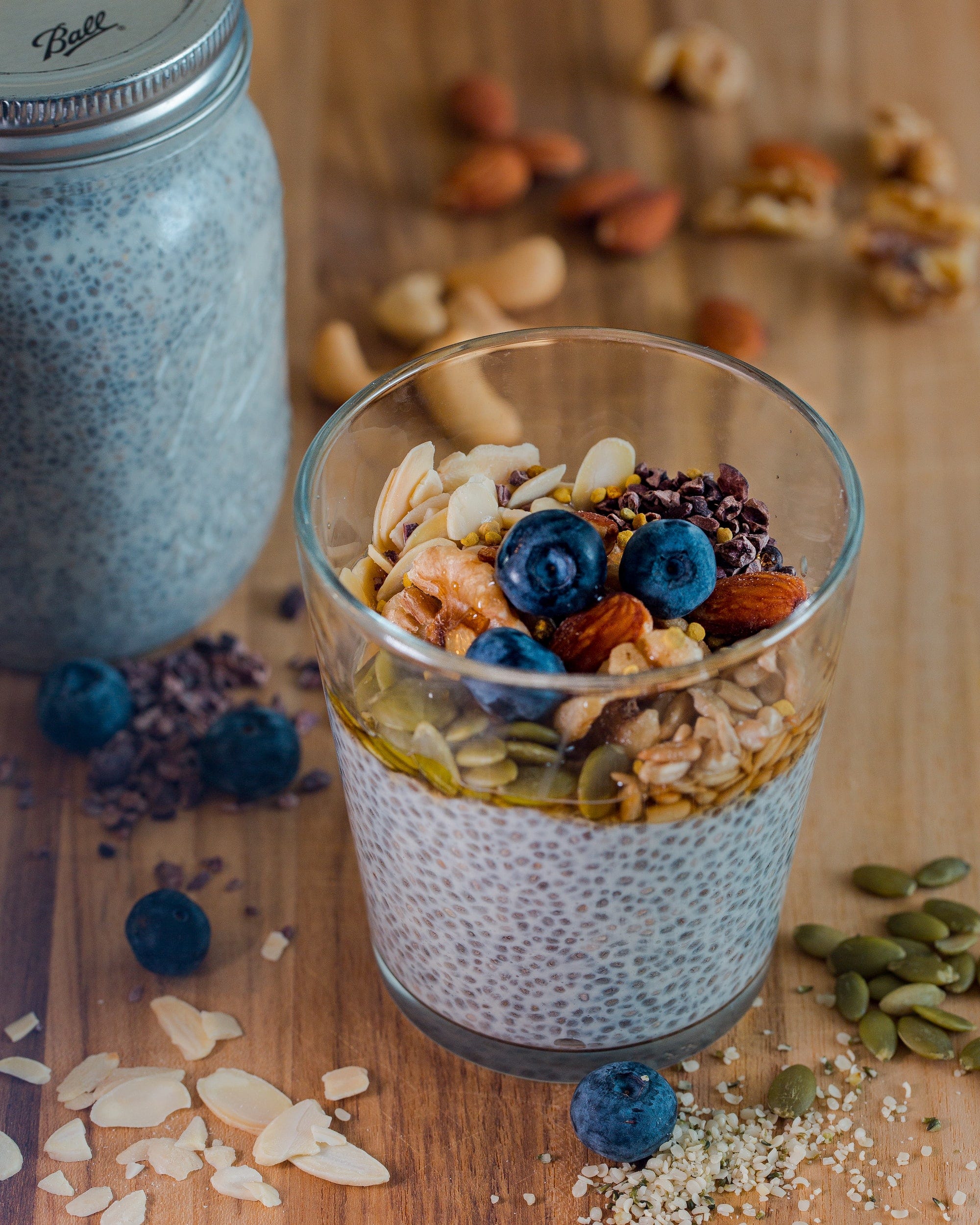 A glass with a smoothie partly made from chia seeds with a jar of the seeds on the side