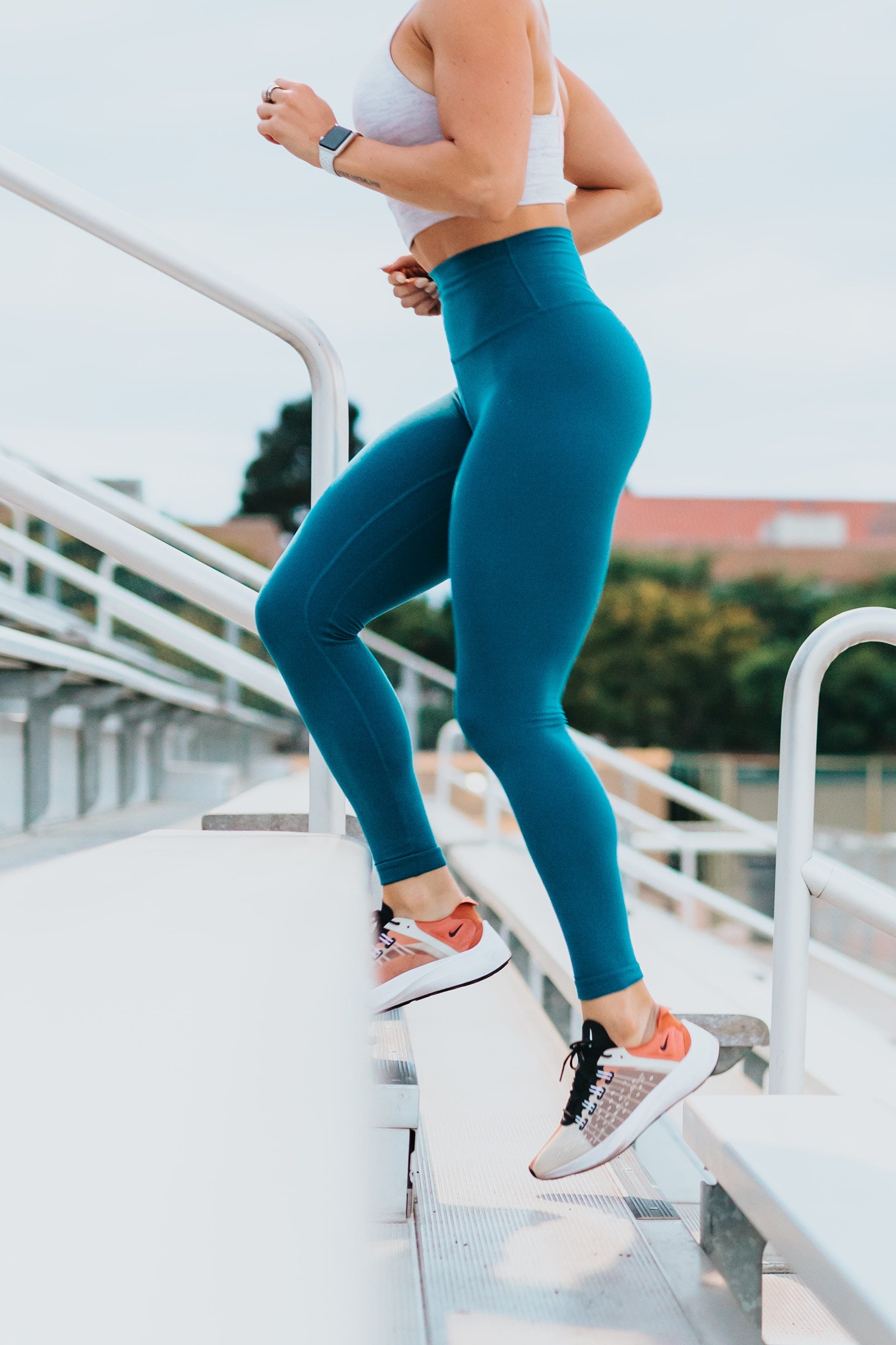 A woman running up a flight of stairs in her gym clothes