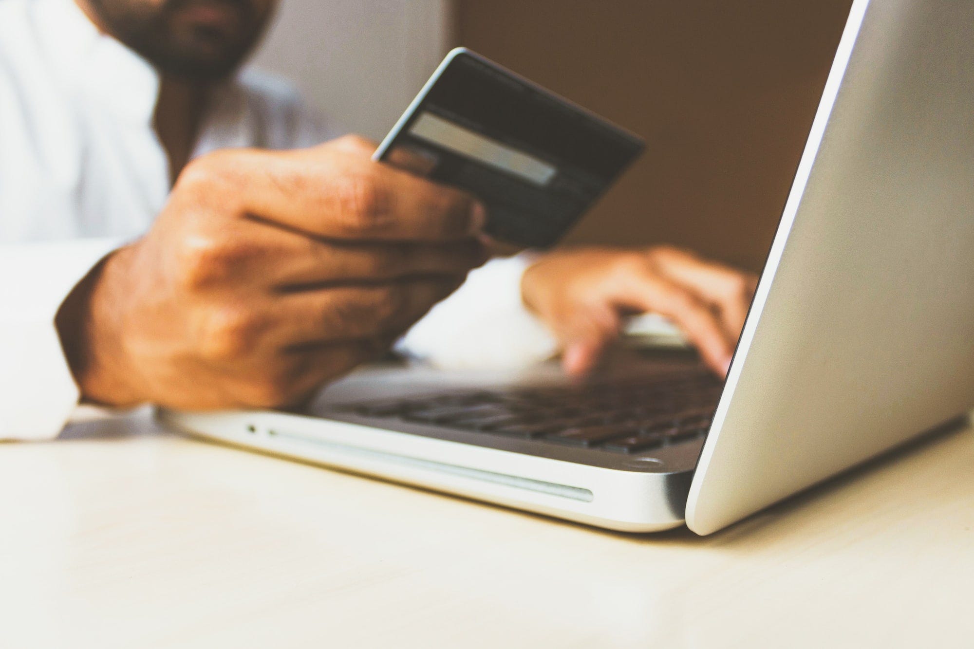 An image of a man keying in his credit card details on a laptop