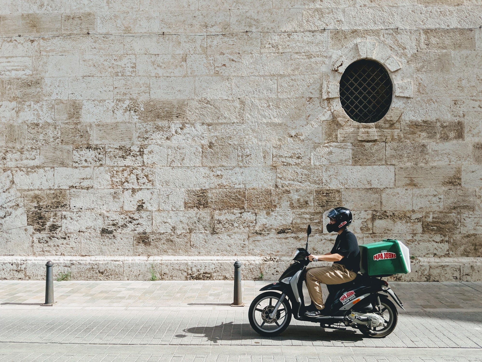 A delivery boy on the old streets of Valencia on a scooter