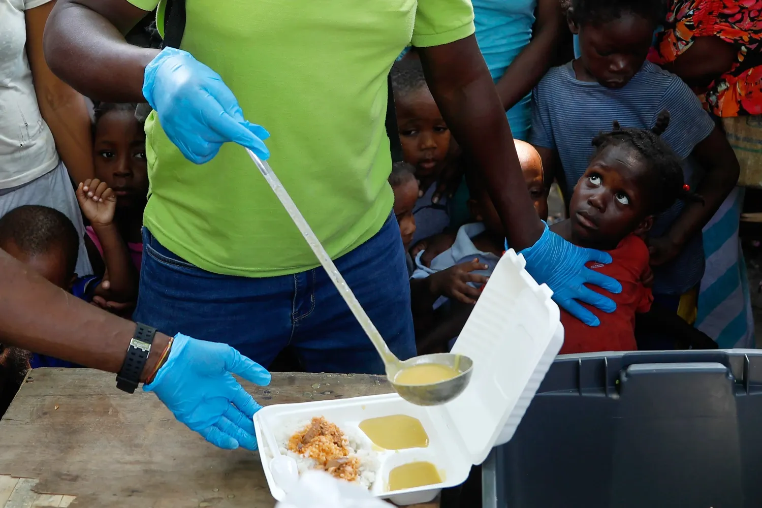 A social worker serving food to Haitian children | Gangs and Insecurity: Investigating the Root Causes of Instability in Haiti | Featured Stories on Mania Africa